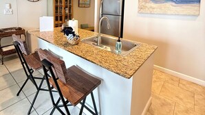 A kitchen with a granite countertop, stainless steel appliances, and a bar stool seating area. - Beautiful 2/2 Condo at Sterling Reef~Great location~Sleeps 6~Beach svc. included (Panama City Beach)