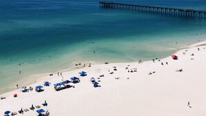 A beach with a pier extending into the ocean, clear skies, and people sunbathing. - Beautiful 2/2 Condo at Sterling Reef~Great location~Sleeps 6~Beach svc. included (Panama City Beach)