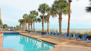 A swimming pool with blue lounge chairs and palm trees. - Beautiful 2/2 Condo at Sterling Reef~Great location~Sleeps 6~Beach svc. included (Panama City Beach)