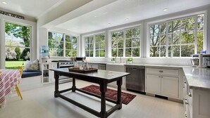 A modern kitchen with large windows, white cabinetry, and a central island. - Southampton Home #6 (Southampton)