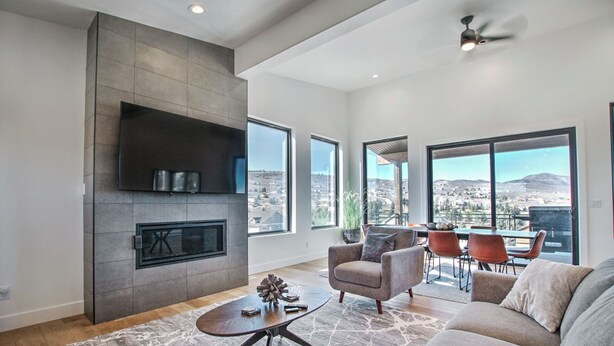 A spacious living room with a fireplace, large windows offering a view of the city, and a cozy seating area.
