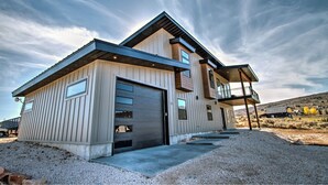 A modern two-story house with a garage, large windows, and a balcony.