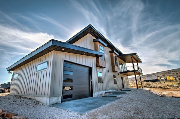 A modern two-story house with a garage, large windows, and a balcony.