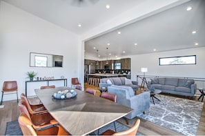 A spacious living area with a dining table, sofas, and a kitchen in the background.