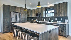 A modern kitchen with dark wood cabinets, stainless steel appliances, and a central island with bar stools.