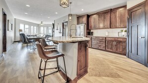 A spacious kitchen with a central island, wooden cabinets, and a bar area with stools.