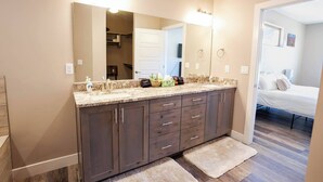 A bathroom with a double sink, dark wooden cabinets, a large mirror, and a fluffy rug on the floor. - Maison Sans Souci - Kanab Home, Pool & Views (Kanab)