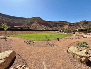 Un área ajardinada con césped, un parque infantil y un edificio de diseño moderno.