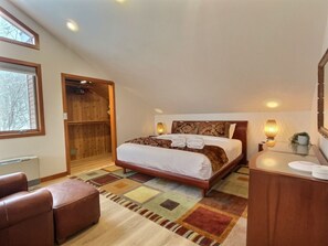 Une chambre à coucher avec un grand lit, une armoire en bois, un bureau avec une lampe et une chaise.