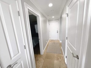 A hallway with white doors, a carpeted floor, and a visible closet with a hanging rack. - Beachfront Hilton Head Resort 2BR (AR-412): Tennis, Pickleball & Largest Pool (Hilton Head Island)