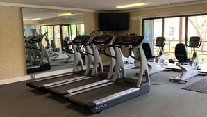 A gym with treadmills, exercise bikes, and a mirrored wall. - Beachfront Hilton Head Resort 2BR (AR-412): Tennis, Pickleball & Largest Pool (Hilton Head Island)