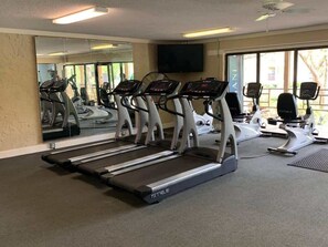 A gym with treadmills, exercise bikes, and a mirrored wall.