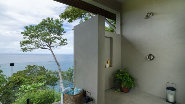A modern bathroom with a view of the sea, a large potted plant, and a built-in sink.