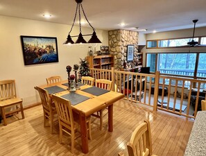 A dining area with a wooden table and chairs, a stone wall, and a view of the outdoors. - Superior Sanctuary on Lake Superior. Just 6 mi from Lutsen Mountain ski resort! (Tofte)