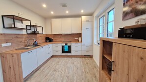 Una cucina moderna con mobili bianchi, piani in legno, forno integrato e macchina per il caffè.