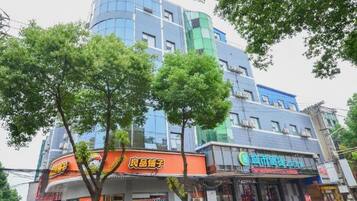 A multi-story building with commercial establishments on the ground floor, surrounded by trees.
