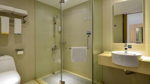 Et moderne badeværelse med en brusekabine i glas, toilet og et spejl over vasken.