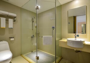 A modern bathroom with a glass-enclosed shower, a toilet, and a sink with a mirror above it.