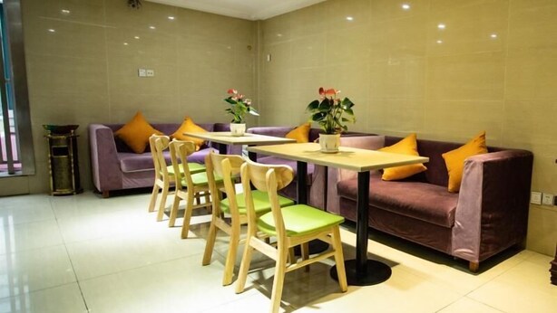 A modern room with a purple sofa, green chairs, a small table, and two potted plants. - Shell Hefei Chaohu Railway Station Wanda Plaza Hotel (Hefei)