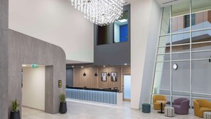 A modern reception area with a counter, seating, and a chandelier. - Hampton by Hilton Doha Old Town (Doha)
