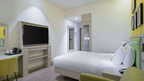 A hotel room with a bed, a desk with a chair, a TV, and a bedside table with a lamp. - Hampton by Hilton Doha Old Town (Doha)