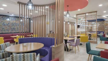 A modern restaurant with booths, round tables, and colorful seating.