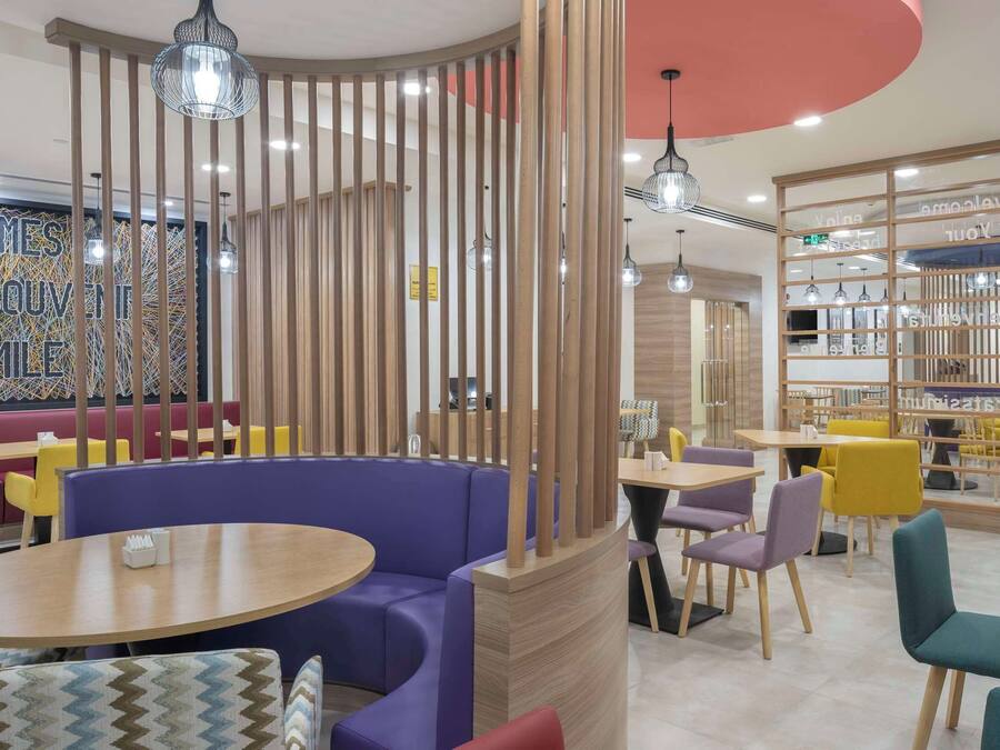 A modern restaurant with booths, round tables, and colorful seating.