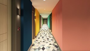 A brightly colored hallway with a geometric patterned floor, leading to a door on the left. - Hampton by Hilton Doha Old Town (Doha)