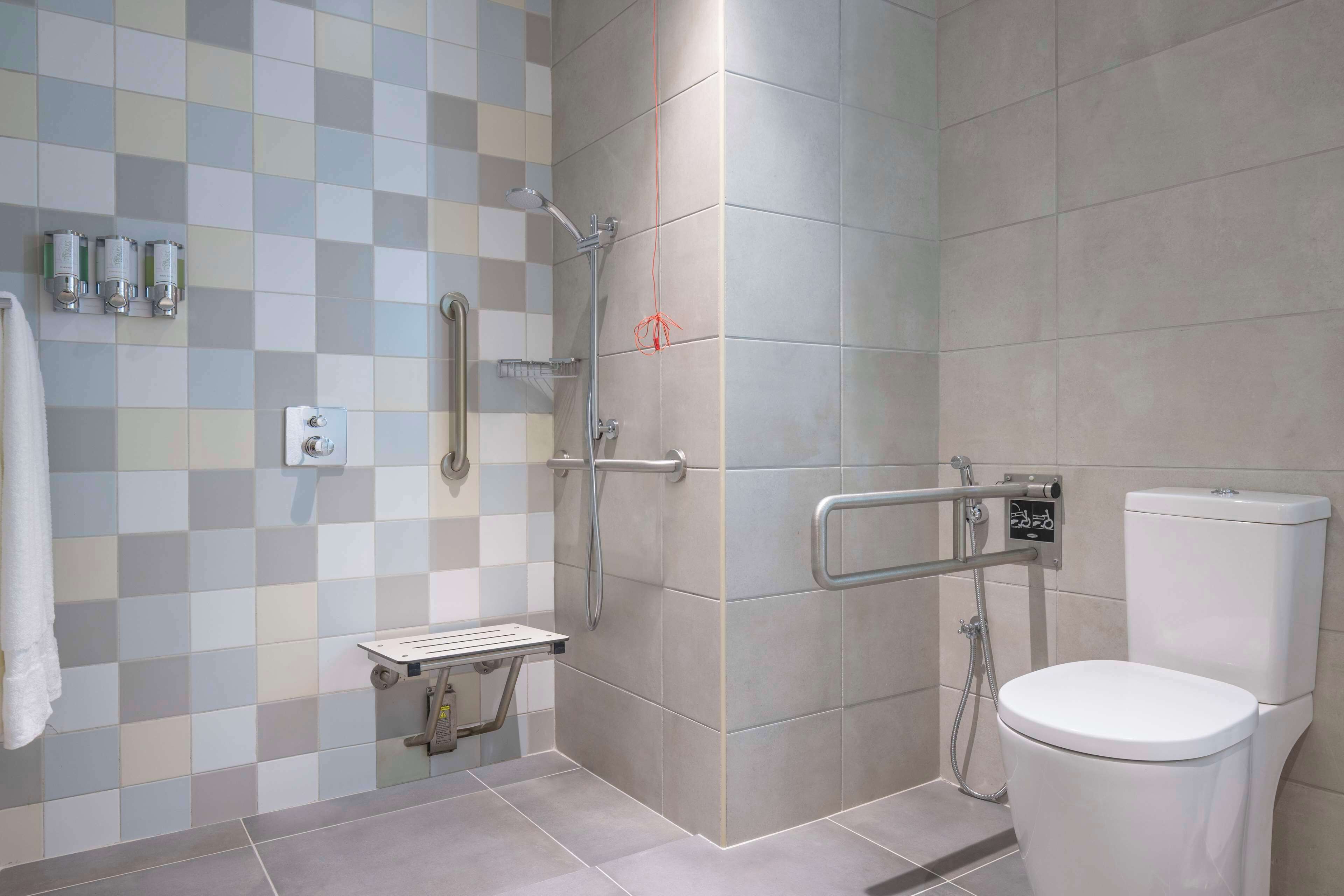Un baño moderno con ducha, inodoro y barras de apoyo.