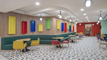 Un interior moderno con un sofá verde, sillas amarillas y rojas, y un suelo estampado.
