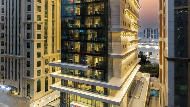 A modern hotel with a prominent 'Hampton' sign, featuring a glass facade and multiple floors. - Hampton by Hilton Doha Old Town (Doha)