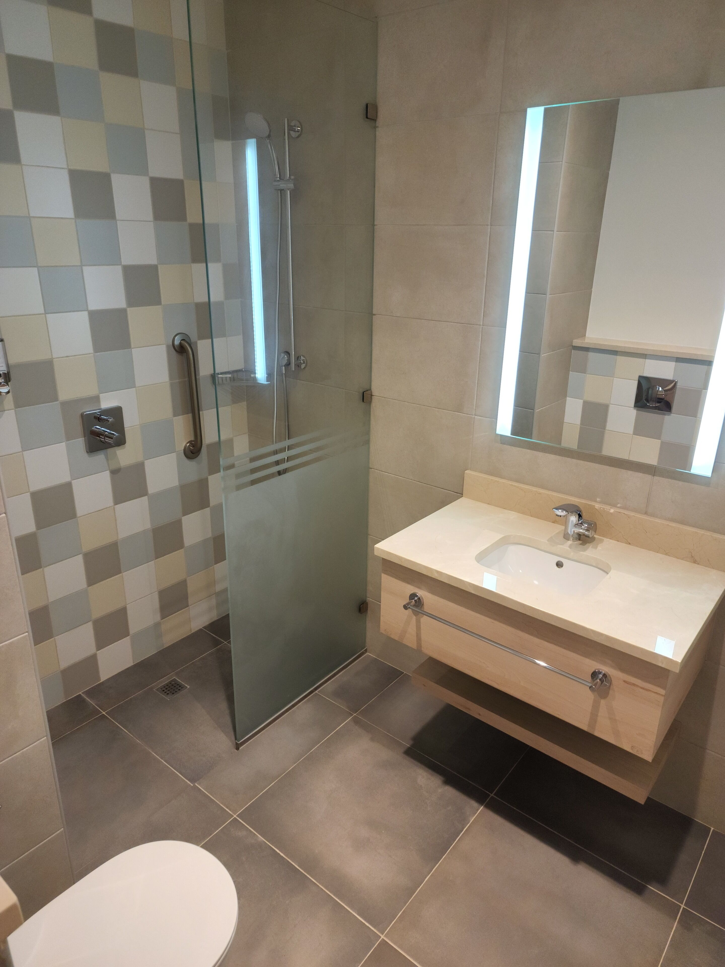 A modern bathroom with a glass shower enclosure, a sink with a mirror, and a toilet.