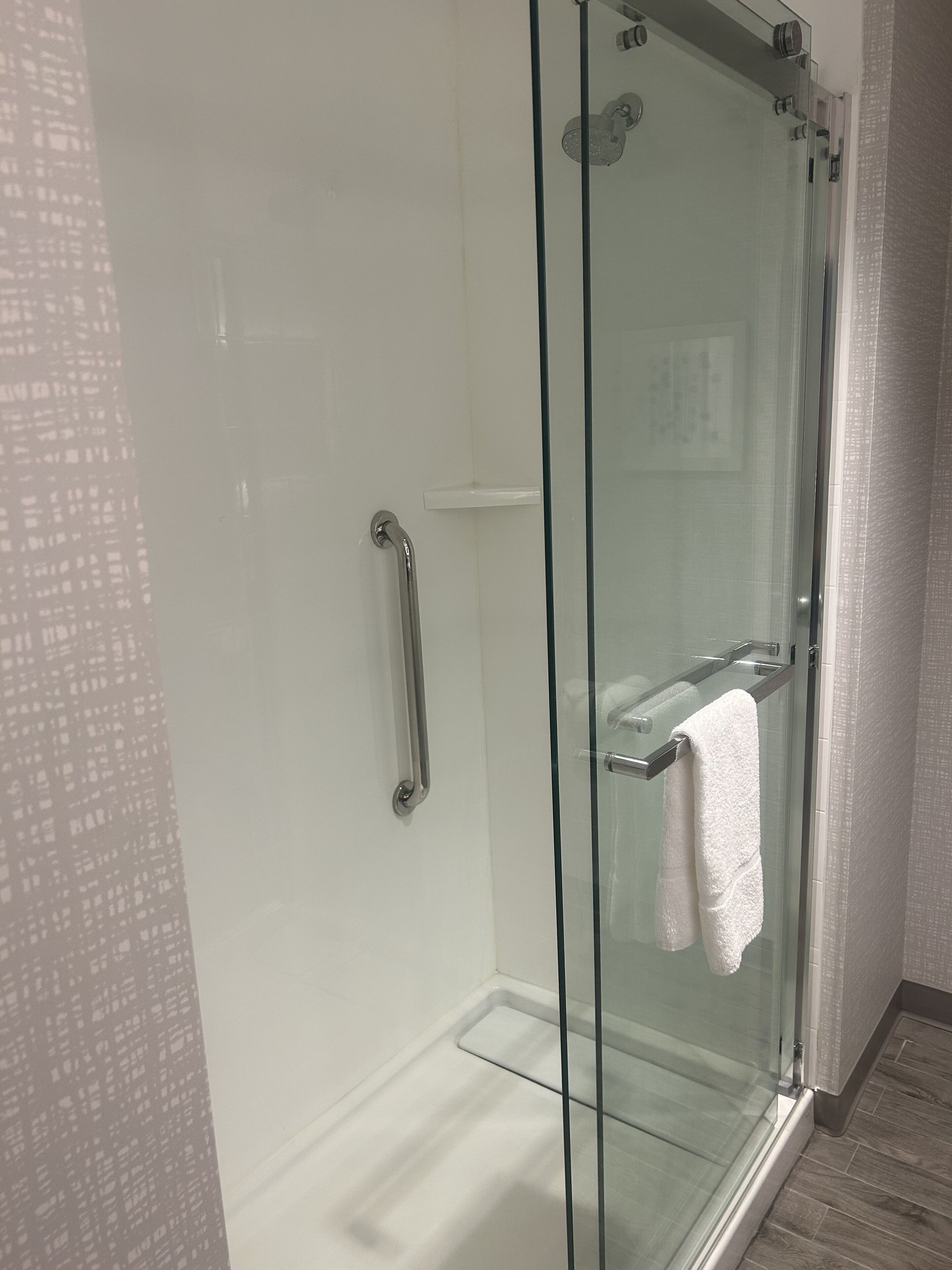 A glass-enclosed shower with a white towel hanging on the door handle.