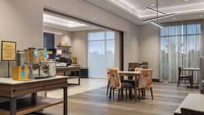 A modern hotel dining area with a breakfast bar, seating arrangements, and a view of the outdoors. - Hampton Inn by Hilton Kingston (Kingston)