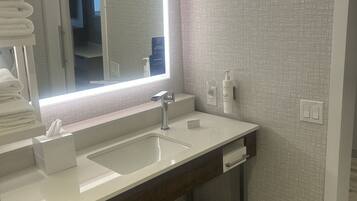 A modern bathroom with a large mirror, two sinks, and a vanity with a wooden cabinet.