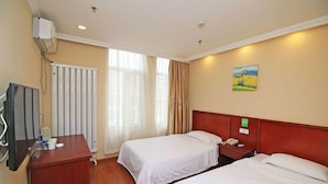 Una habitación de hotel con dos camas, un escritorio, un televisor y un radiador.