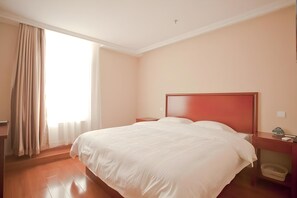A hotel room with a large bed, a wooden nightstand, a bedside table, and a window with curtains. - Greentree Inn Liaoning Dalian Railway Station South Shengli Square Express Hotel (Dalian)