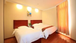 Habitación de hotel con dos camas, piso de madera y un ventanal con cortinas.