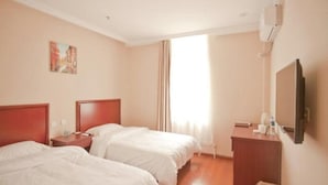 Habitación de hotel con dos camas, un escritorio, una silla, un televisor y una ventana con cortinas.