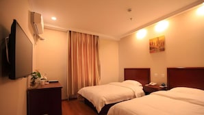 Habitación de hotel con dos camas, televisión, escritorio, cesto de basura y un cuadro en la pared.