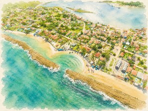 Eine Luftaufnahme einer Küstenstadt mit Strandhäusern, einem Sandstrand und einer felsigen Küstenlinie.