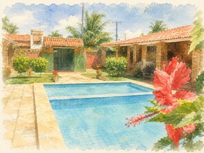 Una piscina con bordo piastrellato, circondata da vegetazione e un edificio con tetto in tegole.