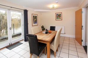 A dining area with a wooden table, four chairs, a radiator, and two framed pictures on the wall. - St Julians Place (Shrewsbury)