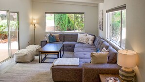 A modern living room with a sectional sofa, ottomans, a coffee table, and a lamp.