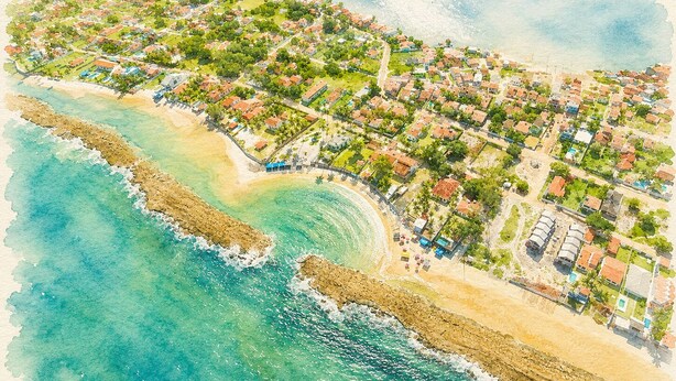 An aerial view of a coastal town with beachfront properties, a sandy beach, and a rocky shoreline.