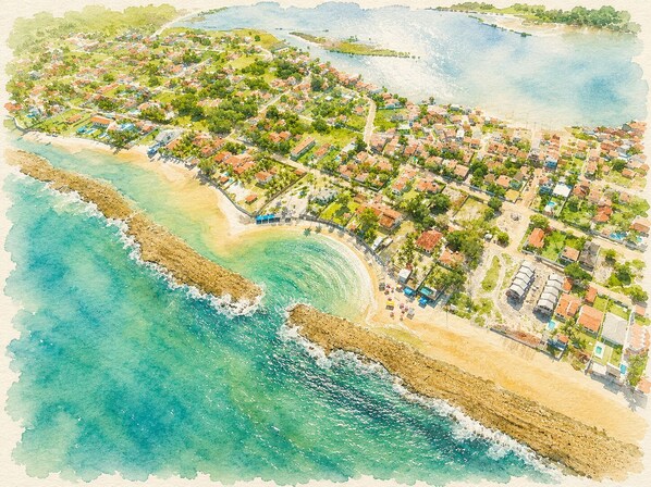 An aerial view of a coastal town with beachfront properties, a sandy beach, and a rocky shoreline.