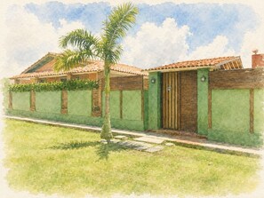 A house with a tiled roof, a green wall, and a palm tree in the front yard.