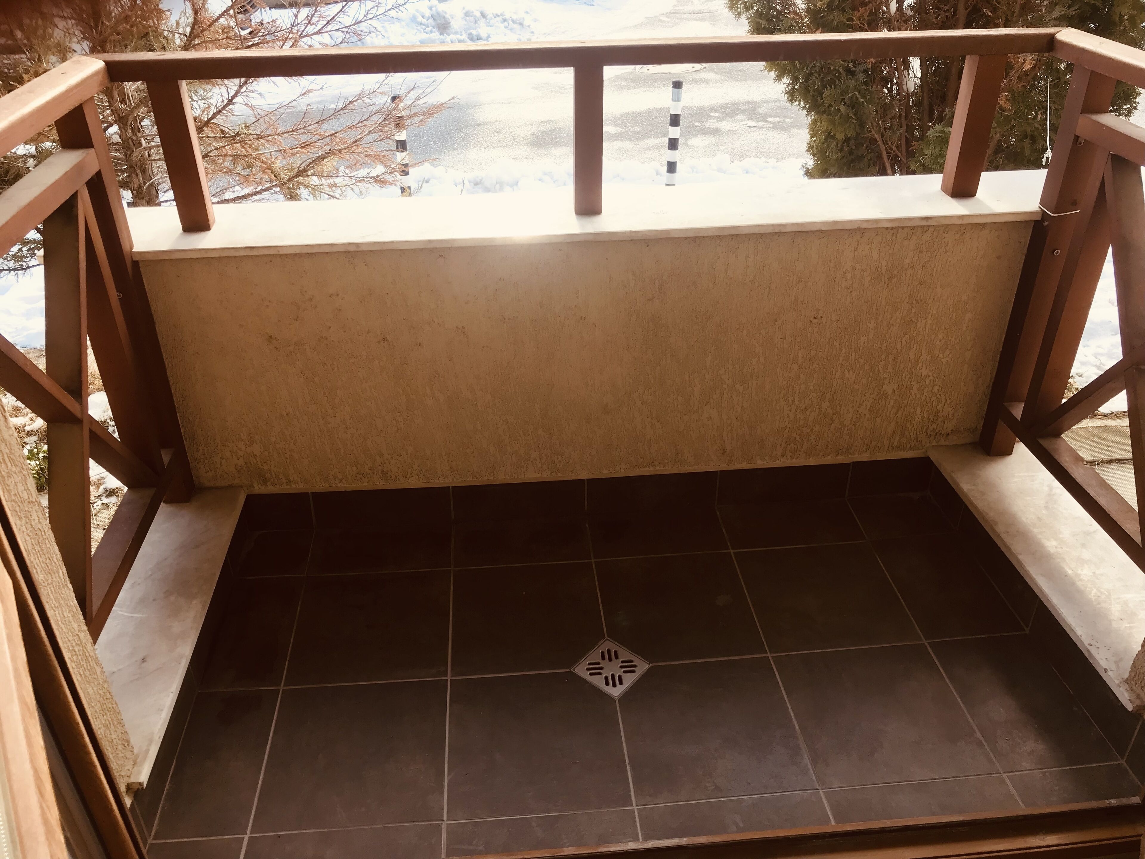 Un balcon doté d’un sol carrelé et de balustrades en bois.