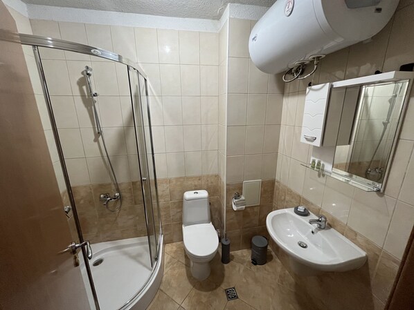 Une salle de bain avec une douche à parois de verre, des toilettes, un lavabo et un miroir.