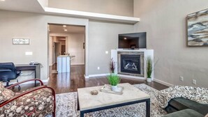 Una sala de estar moderna con chimenea, un comedor y una cocina visibles a través de un vano abierto.